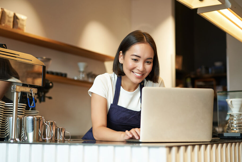 portrait-smiling-asian-barista-cafe-owner-entrepreneur-working-laptop-processing-orders-com
